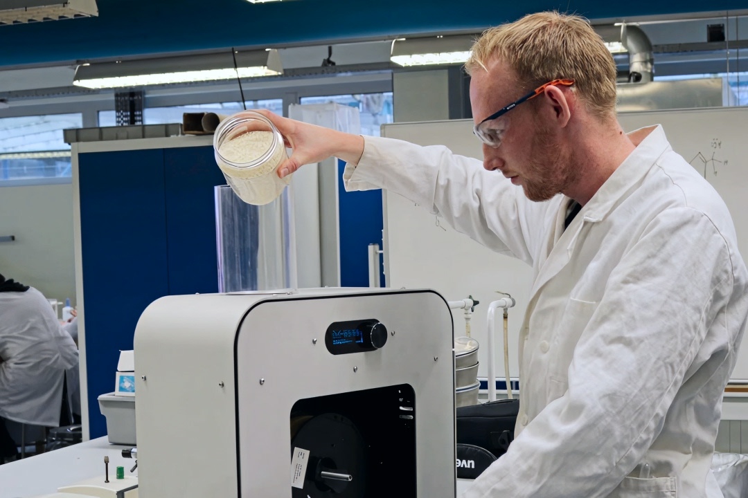Fontys researcher putting Cellulose polymer pellets inside the filament maker