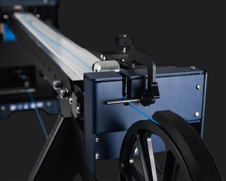 Close-up of the FMX10 conveyor's 3-axis filament sensor and guide pulley near the winder, with blue filament threading through toward the winder.