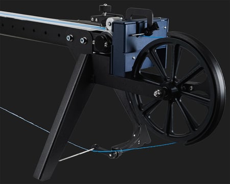 Close-up of the FMX10's winder assembly, showing the large spoked wheel, tensioning arm, and mounting frame.