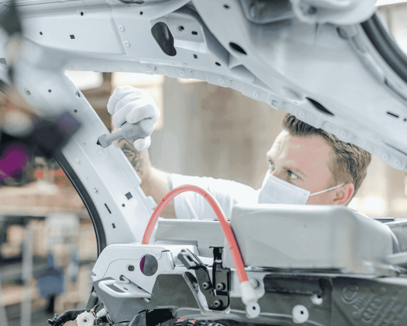 Audi engineer using 3d printed parts while working on a car's skeleton.