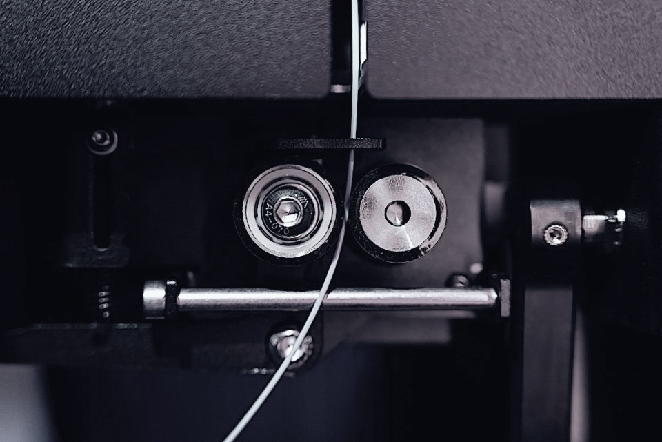 The puller wheels guiding light blue filament onto the spool