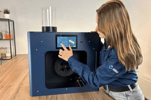 A woman tweaking the Filament Maker TWO's settings from its touchscreen interface.