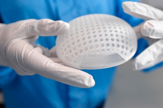 Medical researcher holding a biocompatible 3D printed element.
