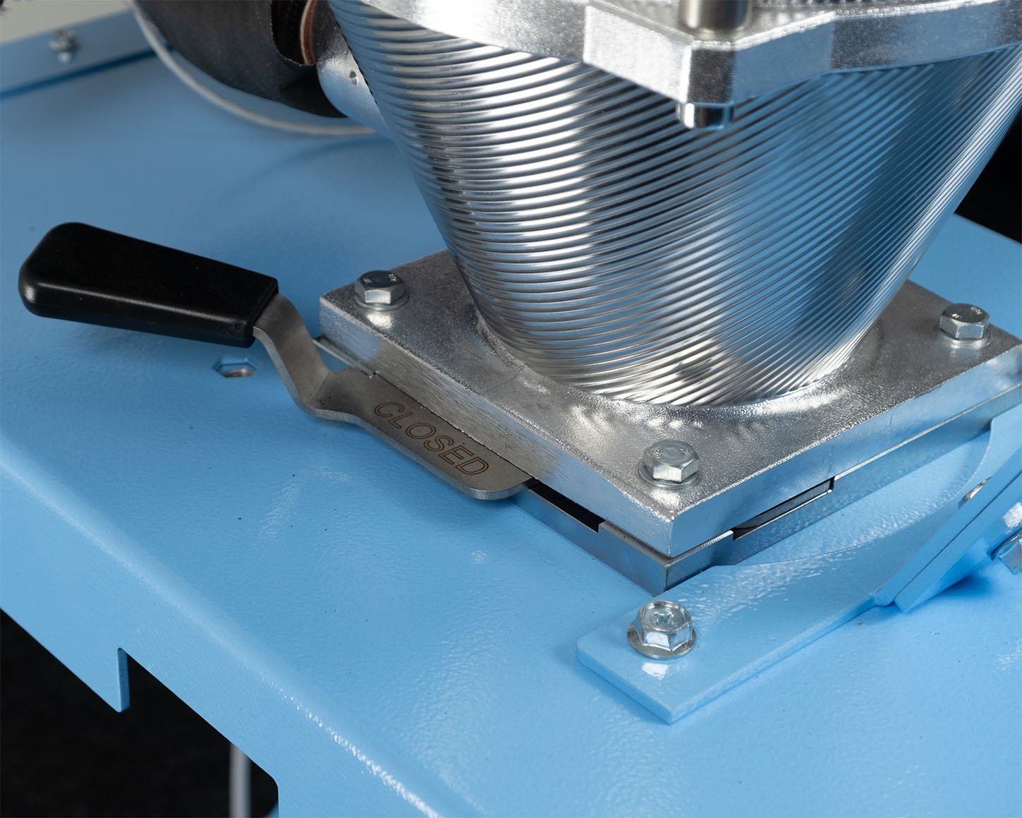 Close-up of the manual slide gate at the XD12 desiccant dryer's hopper outlet, shown in the closed position on the trolley mounting plate.